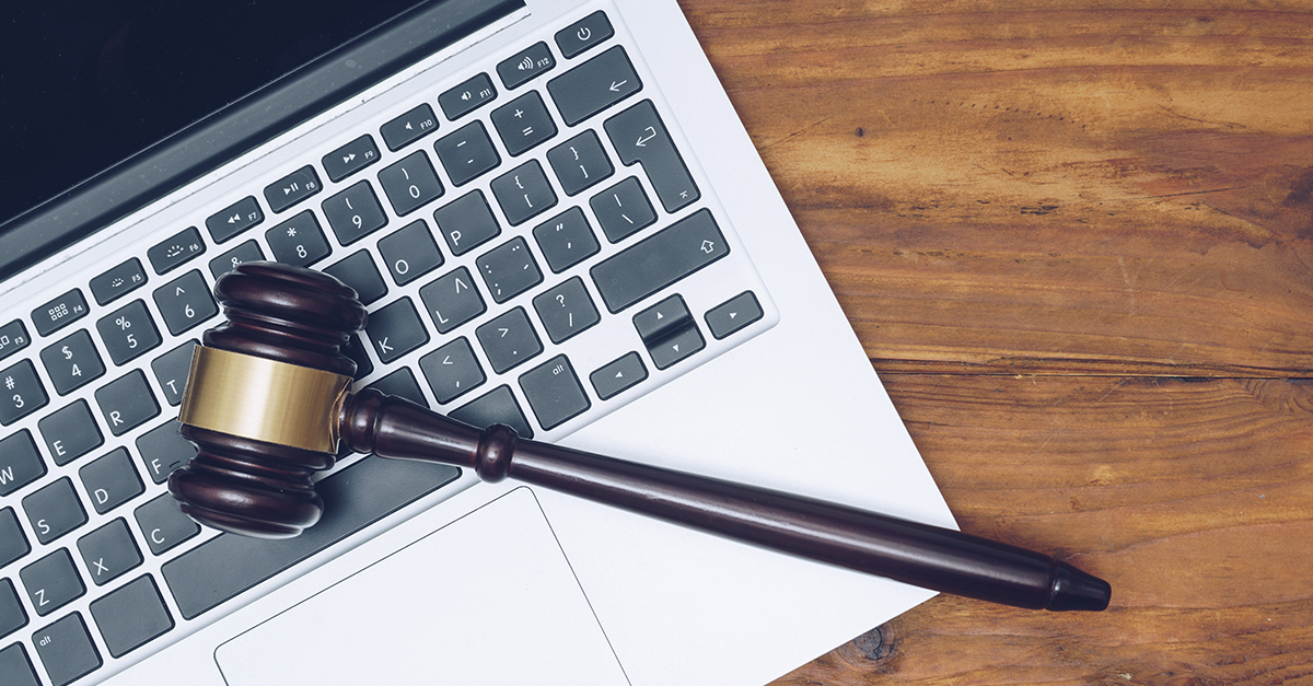 Imagem de um notebook onde em cima das teclas está um martelo da justiça