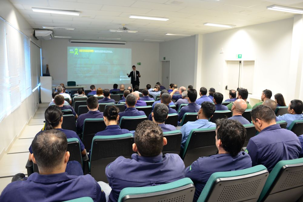A imagem mostra trabalhadores durante palestra sobre segurança e saúde no trabalho.