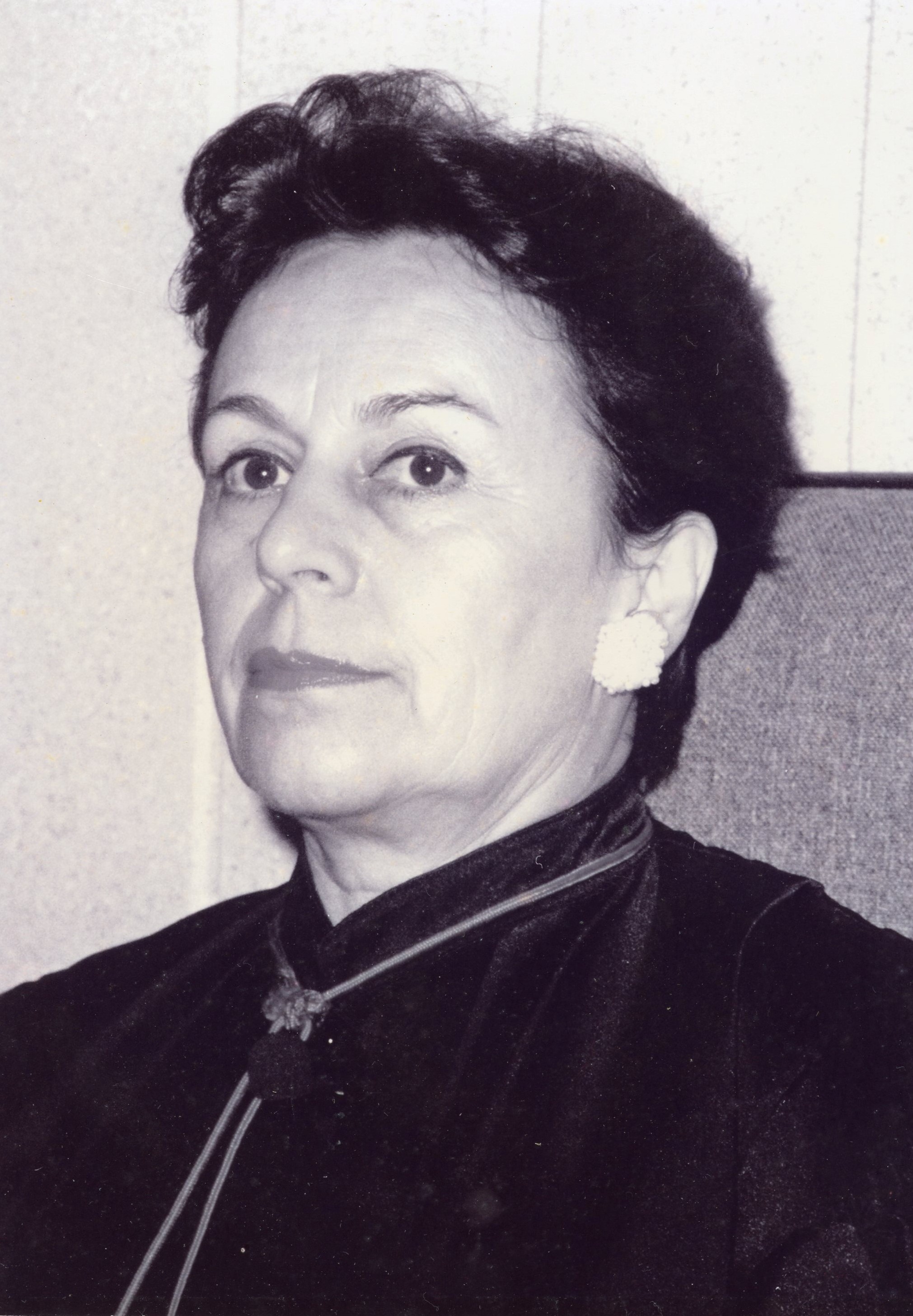 Fotografia em preto e branco, mulher branca, cabelos negros, curto, usando toga.