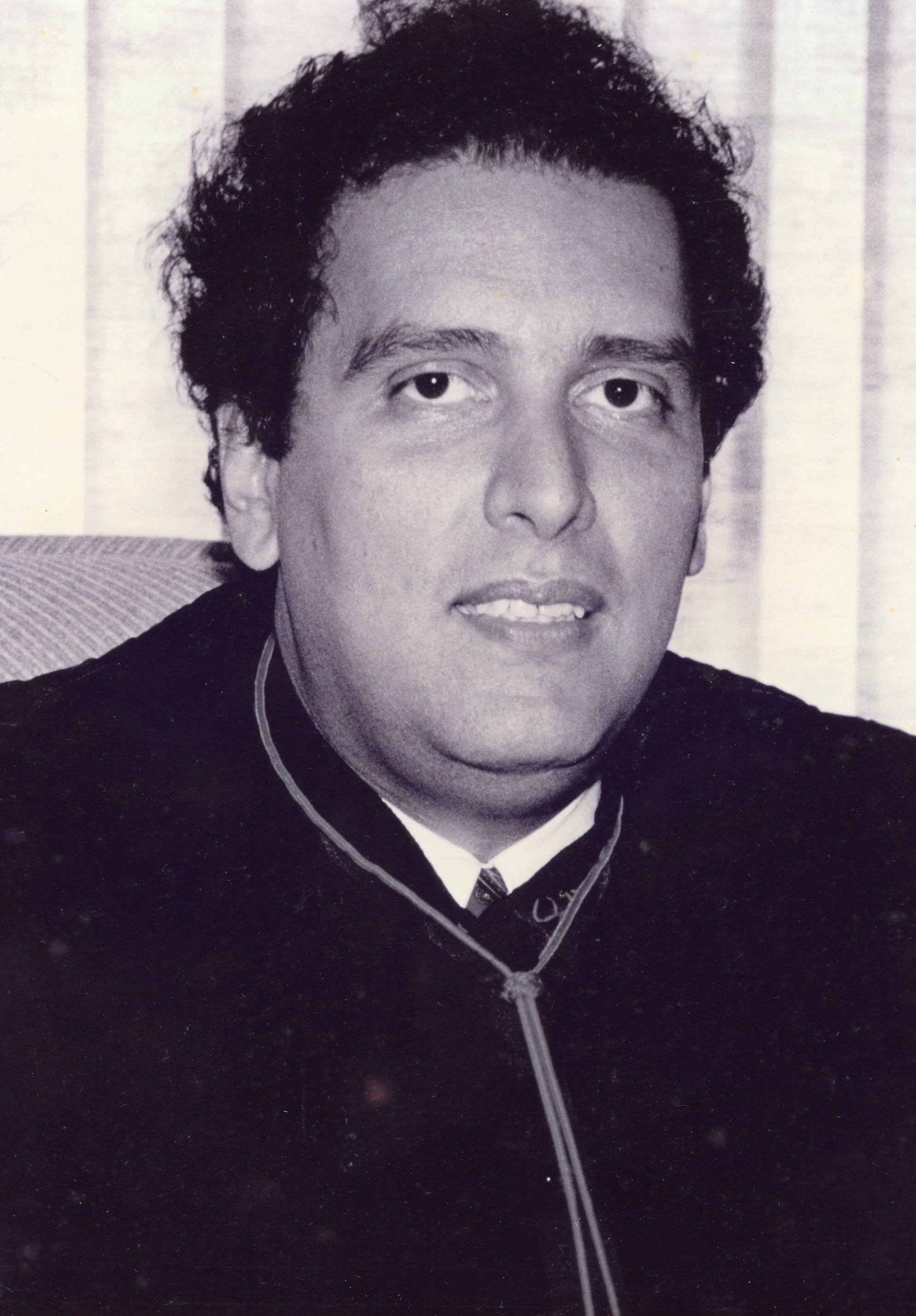 Fotografia em preto e branco, homem pardo, cabelo preto, usando toga