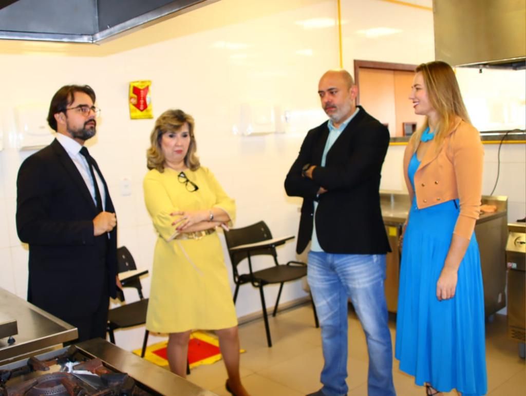 A foto mostra duas mulheres e dois homens conversando em uma sala.