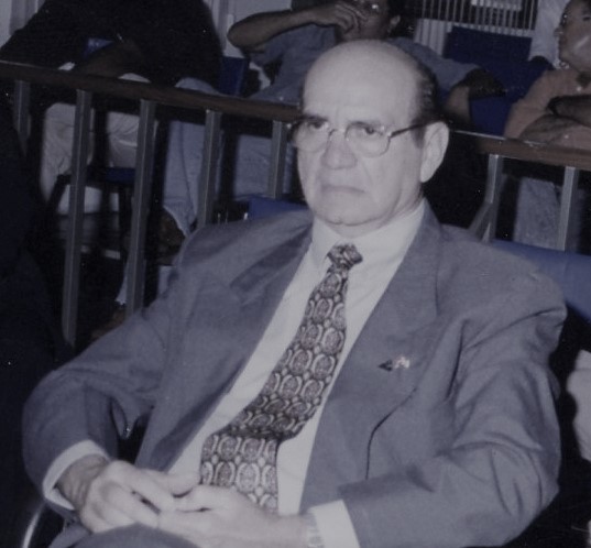 Homem branco, cabelo preto, usando paletó