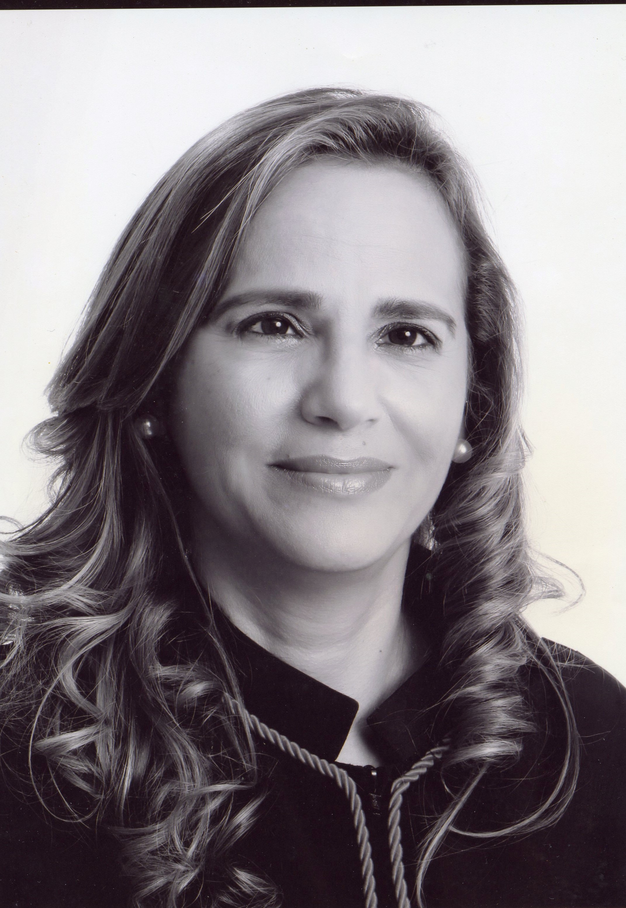 Fotografia em preto e branco, mulher branca, cabelos negros, médio, usando toga.