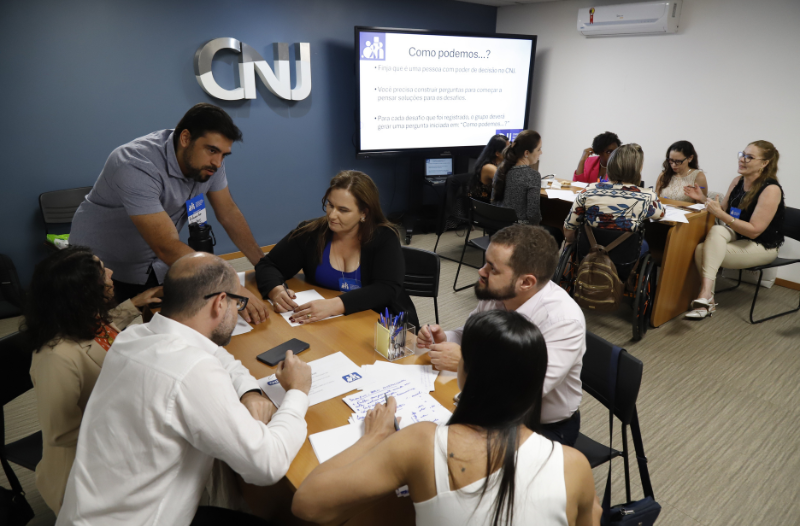 equipe de servidores(as) em volta de uma mesa em oficina de acessibilidade no CNJ