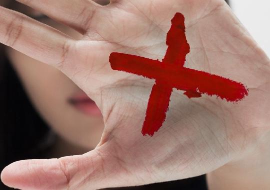 Imagem mostra X vermelho desenhado na palma da mão,  sinal de pedido de socorro e denúncia de violência doméstica ou familiar.