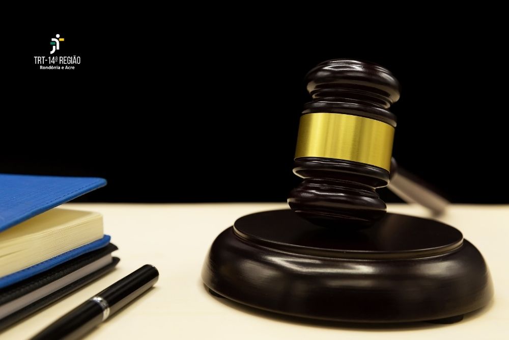 A imagem mostra um martelo, um livro e uma caneta sobre uma mesa.